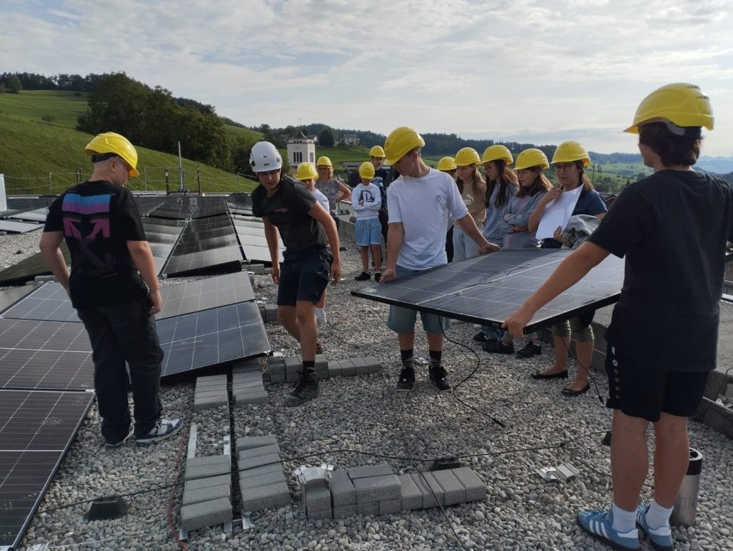 Jugendliche helfen mit, eine Solaranlage auf dem Schulhausdach zu installieren