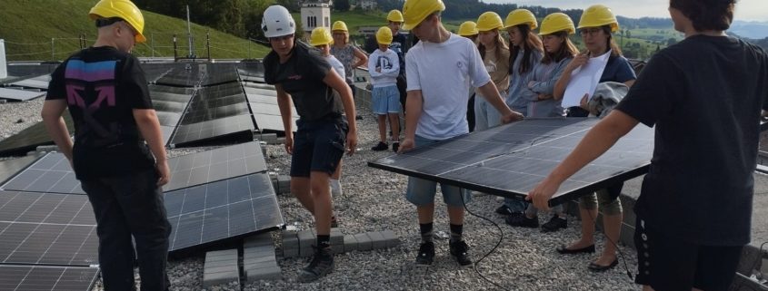 Jugendliche helfen mit, eine Solaranlage auf dem Schulhausdach zu installieren