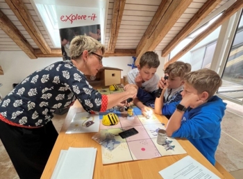 Petra Kohler erklärt einigen Kindern eine Aufgabe im Experimentierlabor