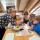 Petra Kohler erklärt einigen Kindern eine Aufgabe im Experimentierlabor