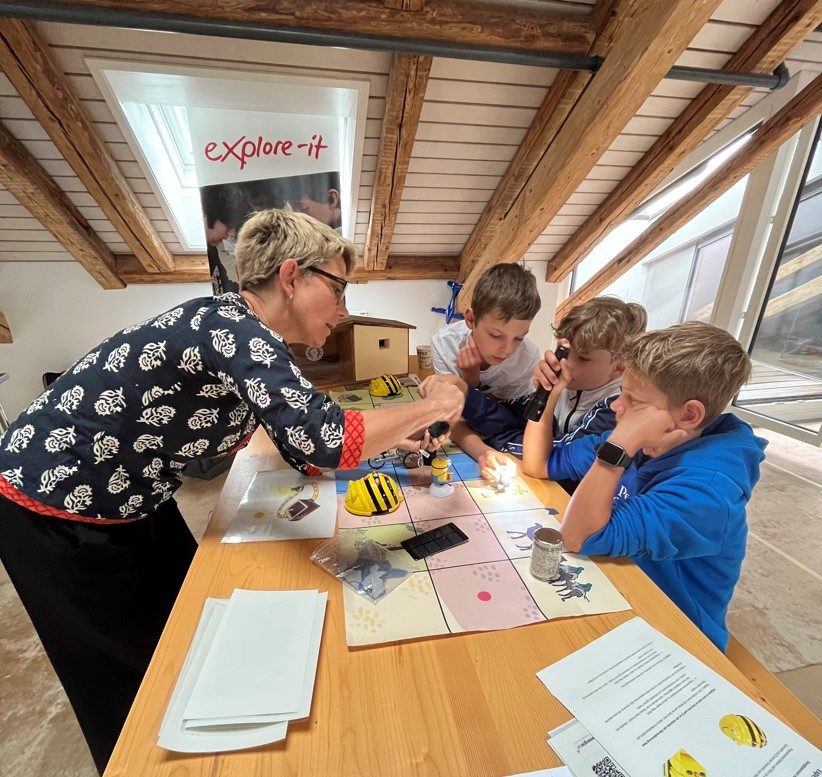 Petra Kohler erklärt einigen Kindern eine Aufgabe im Experimentierlabor