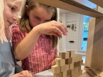 Zwei Mädchen bauen eine Pyramide aus Holzwürfelchen