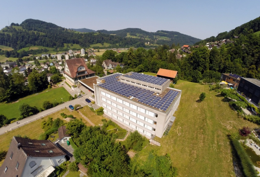 Schulanlage Risi in Wattwil mit grosser PV-Anlage, im Hintergrund das Dorf Wattwil