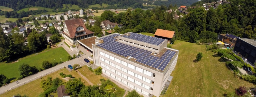 Schulanlage Risi in Wattwil mit grosser PV-Anlage, im Hintergrund das Dorf Wattwil