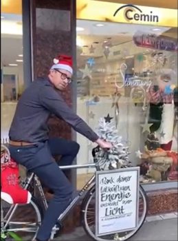 Mann mit einer Weihnachtsmütze sitzt auf einem Velo und pedalt