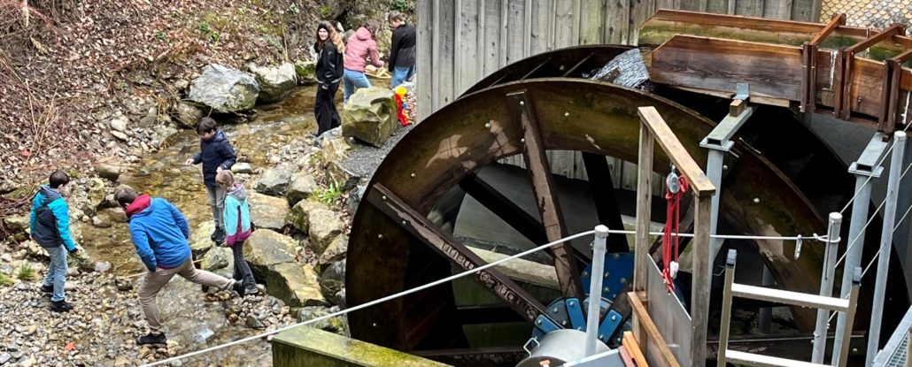 Wasserrad am Hagtobelbach mit einer Schulklasse, die experimentiert
