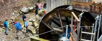 Wasserrad am Hagtobelbach mit einer Schulklasse, die experimentiert