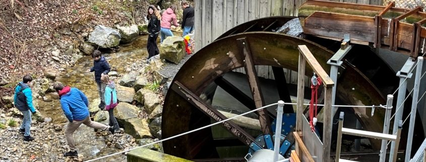 Wasserrad am Hagtobelbach mit einer Schulklasse, die experimentiert