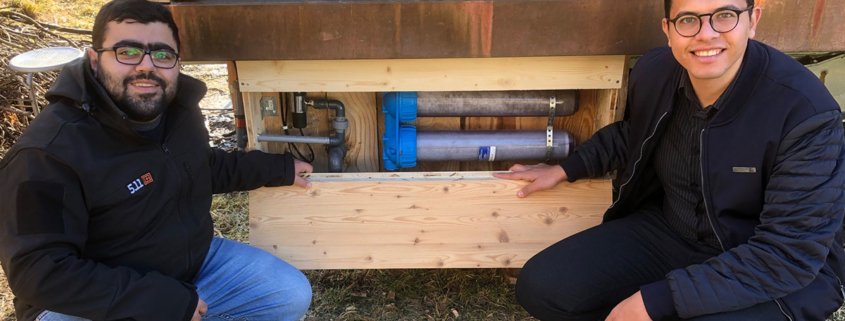 Zwei Arbeiter zeigen die Grauwasseraufbereitungsanlage am Eventhaus