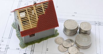 Modellhaus auf Bauplan mit Bargeld